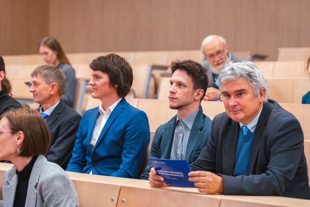 Nove doktorice in doktorji skupaj z mentorji in ostalim občinstvom v predavalnici.