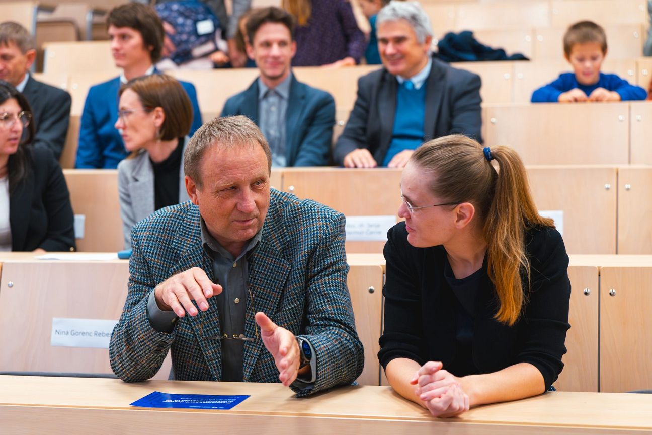 Nove doktorice in doktorji skupaj z mentorji in ostalim občinstvom v predavalnici.